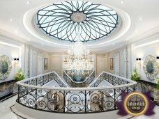 The picture shows a brown and white horse in a grassy field with a cloudy sky in the background. The horse is wearing a green blanket, and it appears to be looking out of the frame.