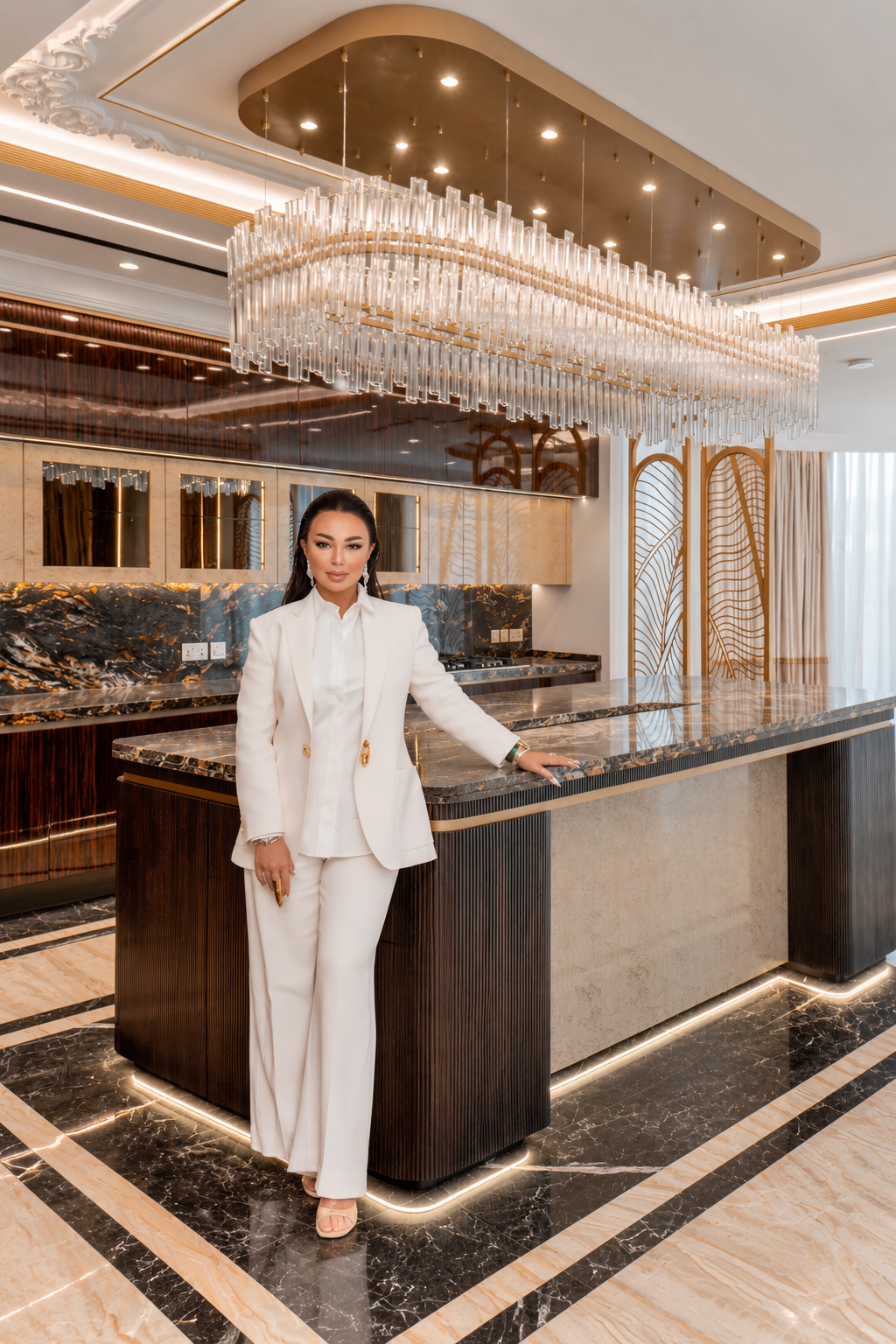 Designer standing at a dark wood kitchen island under a crystal chandelier