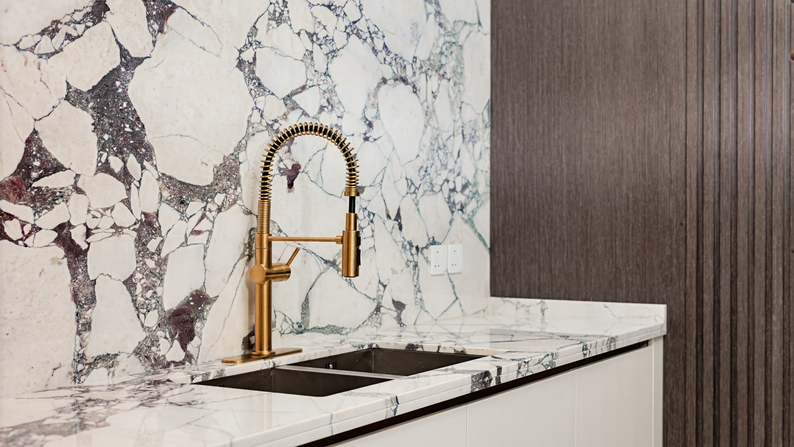Marble backsplash and worktop with a brushed brass kitchen tap